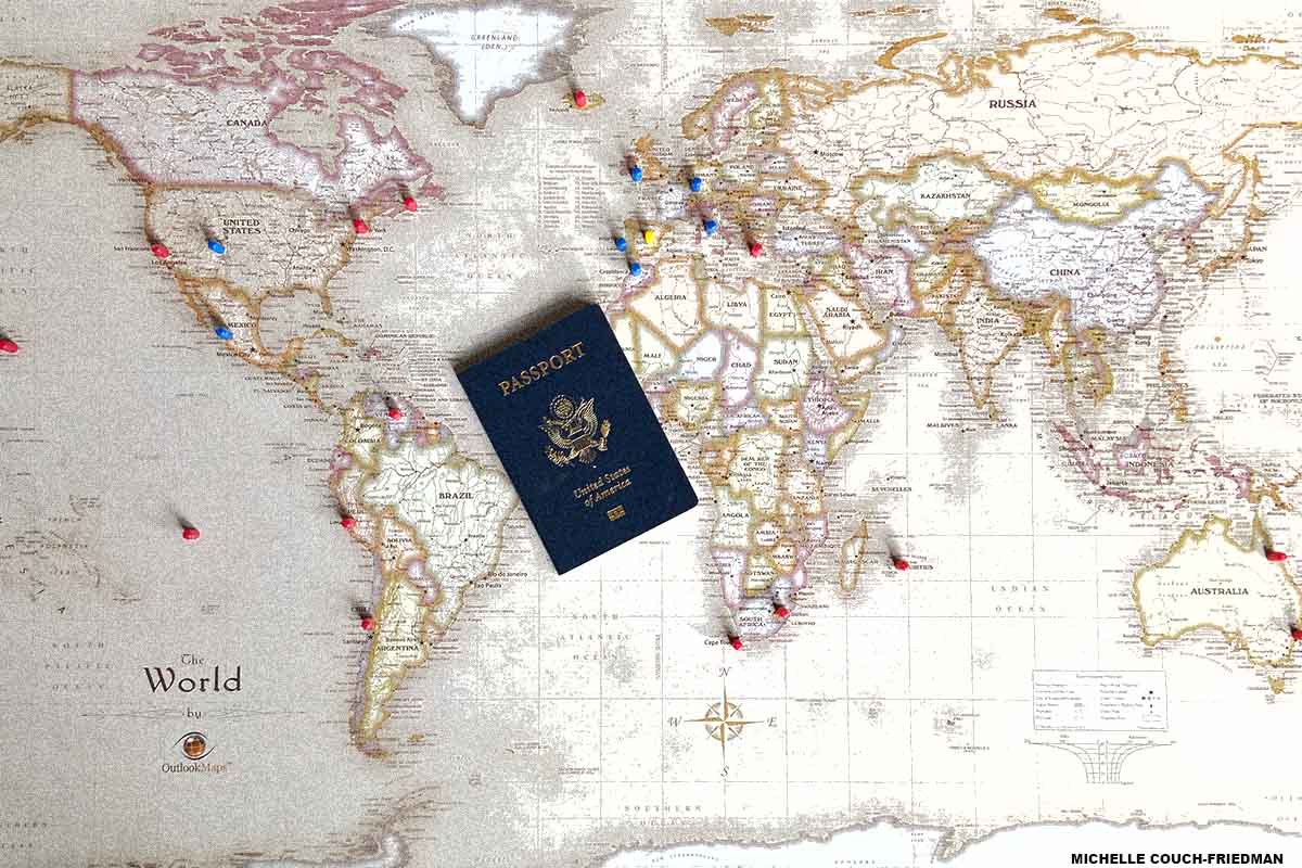 A U.S. passport on top of a white and brown world map