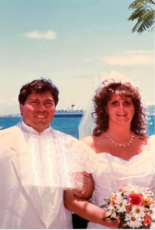 A wedding couple in front of Norwegian Cruise Line's SS Norway, a tropical wedding scene, bride and groom. cruise ship floating in the ocean behind a wedding on the beach.