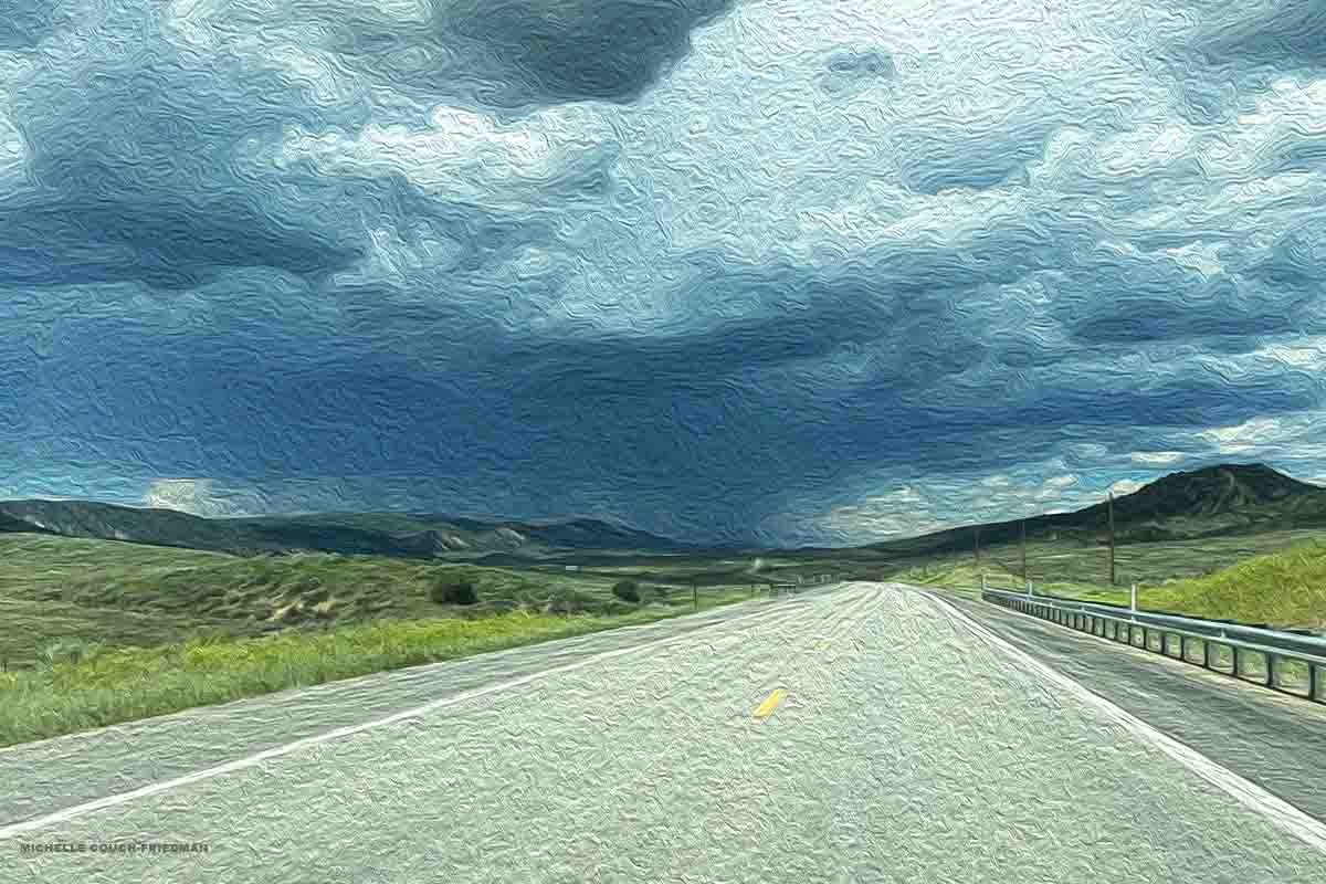 An isolated road with storm clouds on the horizon, Avis customer charged $8,000 after it rental car experienced total mechanical failure on a road trip. Original photo by the author Michelle Couch-Friedman.
